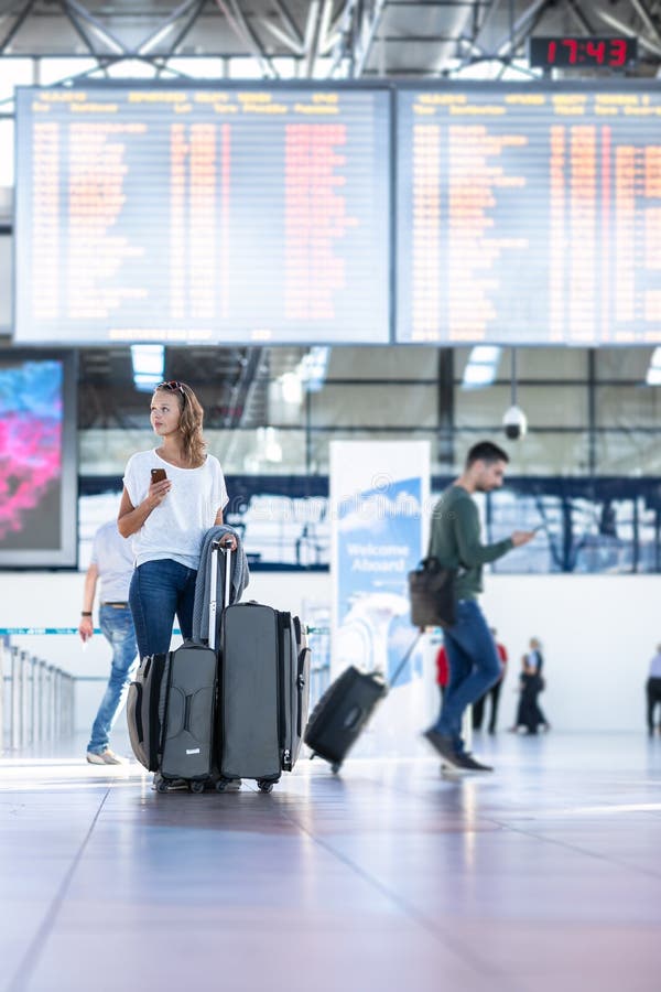 Young woman with her luggage at an international airport, before going through the check-in