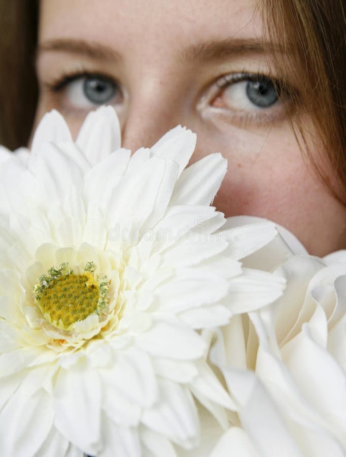 Young woman hiding her face with white flowers