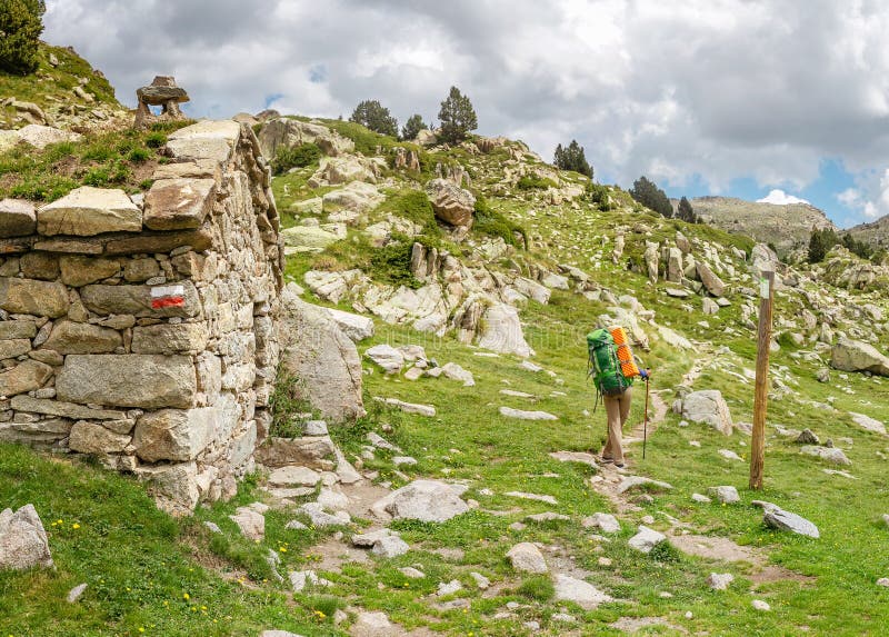 Woman hiker camping near the beautiful shelter stone hut building in Pyrenees mountains. Hiking and adventure concept