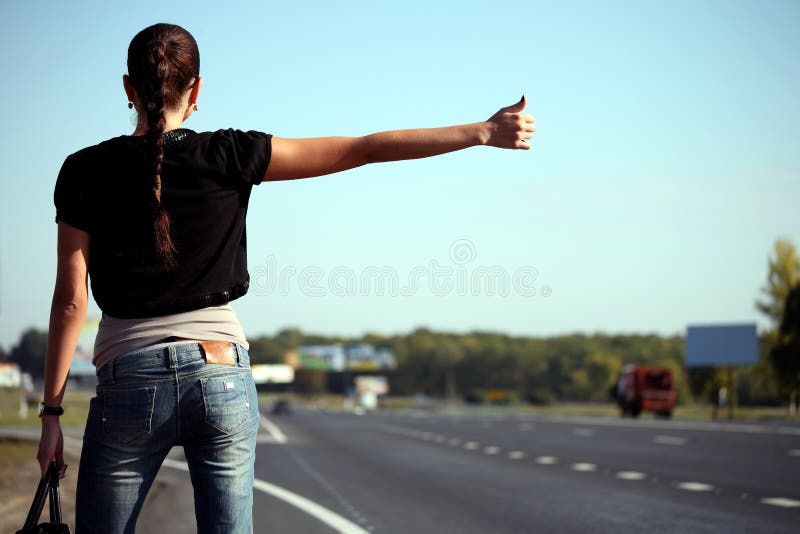 Young woman hitchhiking on the road stock photo Young woman hitchhiking on the road stock photo