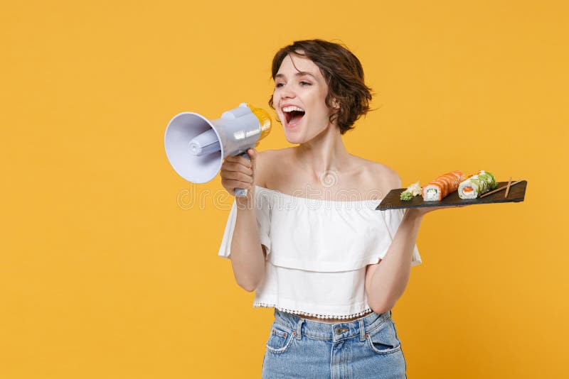 Young woman hold in hand makizushi sushi roll served on black plate japanese food scream in megaphone announces stock image
