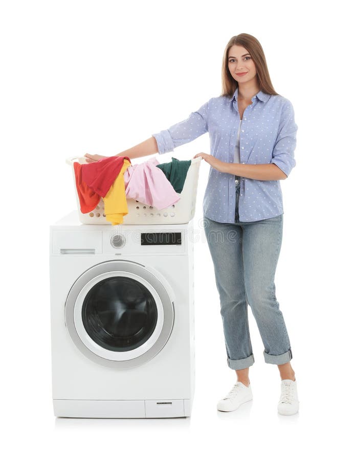 Young woman holding basket with dirty laundry near washing machine