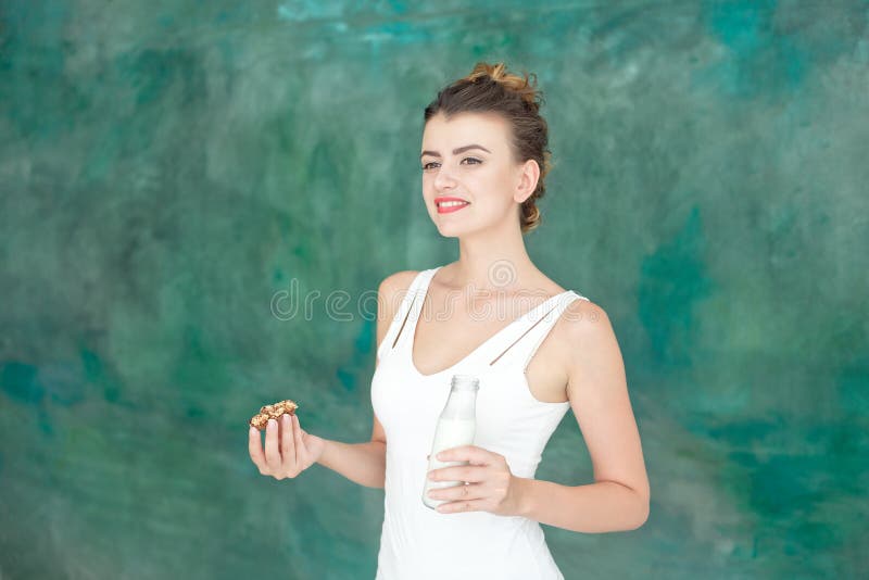 Young woman holding a bottle of milk wearing in white singlet indoor stock photos Young woman holding a bottle of milk wearing in white singlet indoor stock photos