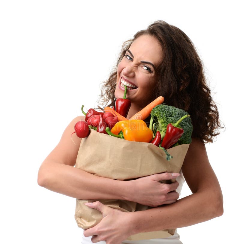 Young woman holding grocery paper shopping bag full of fresh vegetables