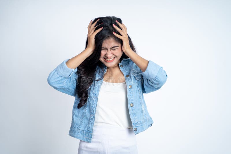 Young woman holding head while confused by situation on isolated background