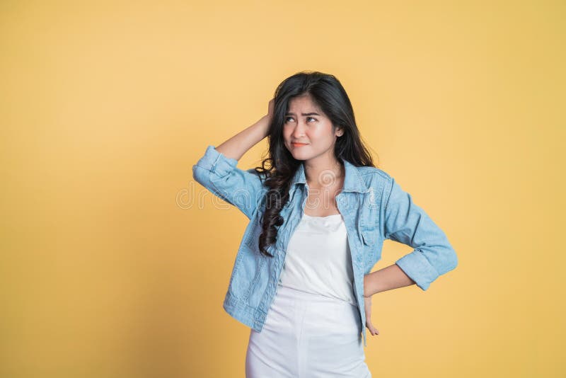 Young woman holding head while confused by situation on isolated background