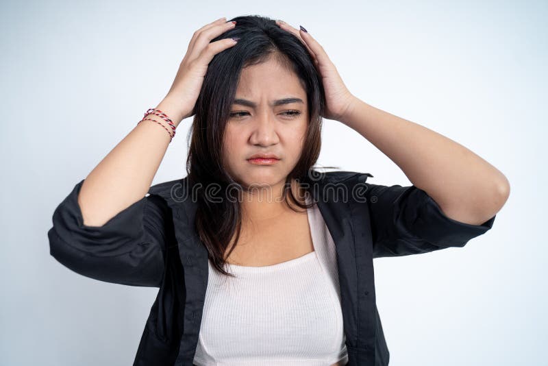 Young woman holding head while confused by situation on isolated background