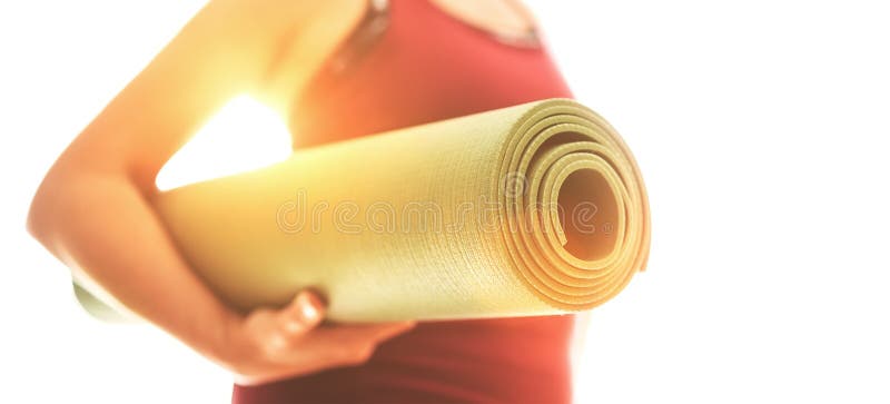 Young Woman holding rolled rubber gymnastic mat starting morning yoga exercises. Active people and healthy lifestyle concept stock image Young Woman holding rolled rubber gymnastic mat starting morning yoga exercises. Active people and healthy lifestyle concept stock image