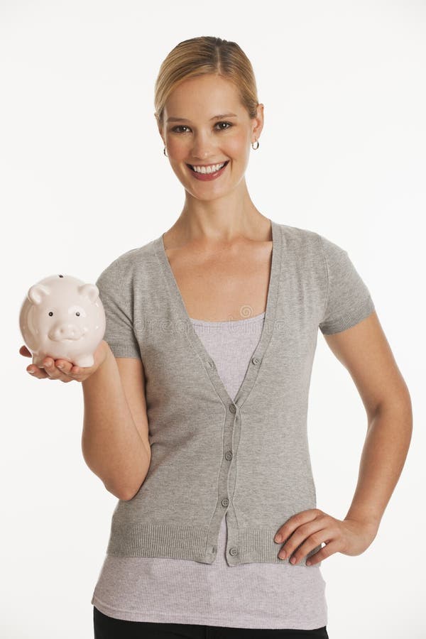 Young woman holding up piggy bank on white seamless background