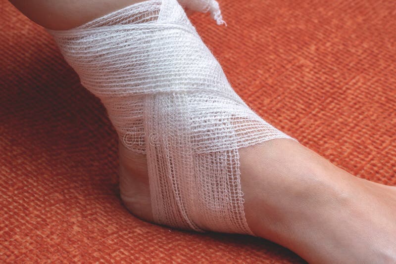 A Young Woman at Home Bandages Her Foot and Lower Leg with a Bandage