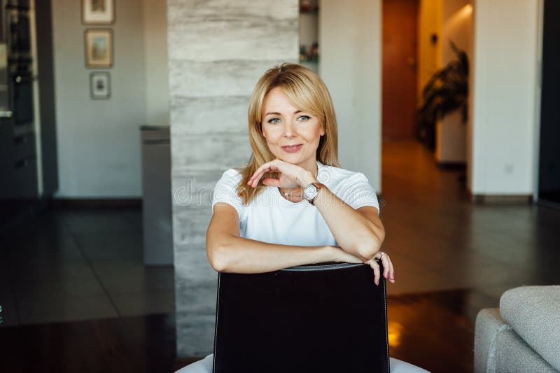 Young woman at home sitting on modern chair near window relaxing in living room royalty free stock photography Young woman at home sitting on modern chair near window relaxing in living room royalty free stock photography