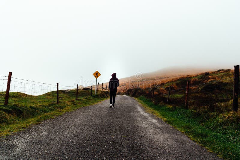 Young woman on hoodie walks on misty road royalty free stock images Young woman on hoodie walks on misty road royalty free stock images