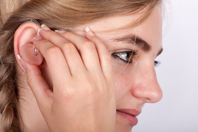 Young woman inserting a hearing aid in her ear