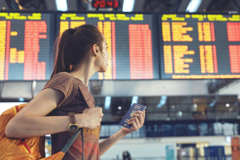 Young woman in international airport looking at the flight information board royalty free stock photography Young woman in international airport looking at the flight information board royalty free stock photography