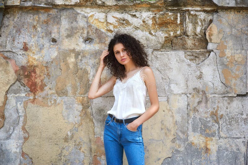Young beautiful woman in jeans and white blouse on old city street royalty free stock photo Young beautiful woman in jeans and white blouse on old city street royalty free stock photo