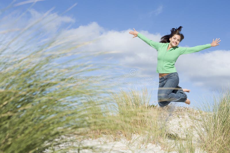 Young woman jumping amongst sand dunes