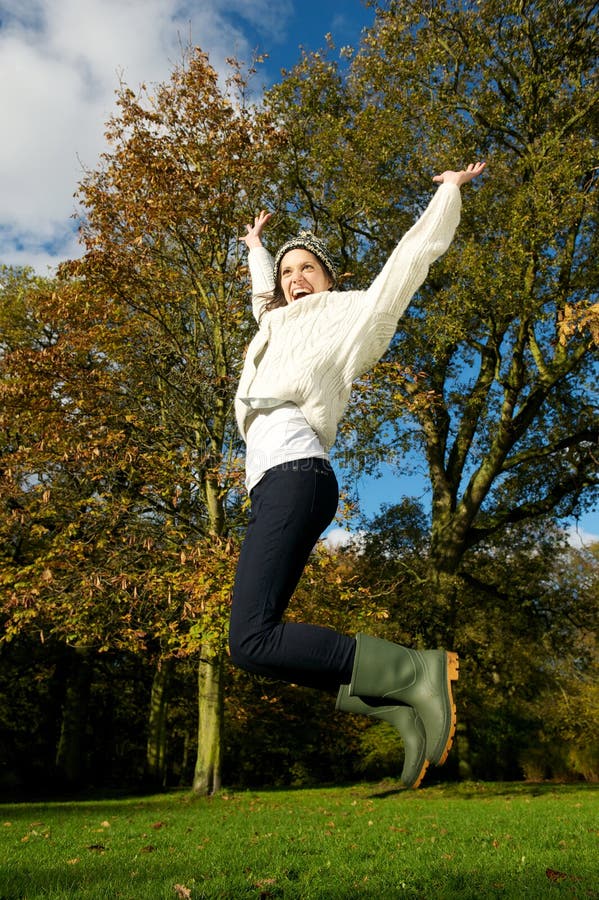 Young woman jumping for joy outdoors on a beautiful fall day stock photos