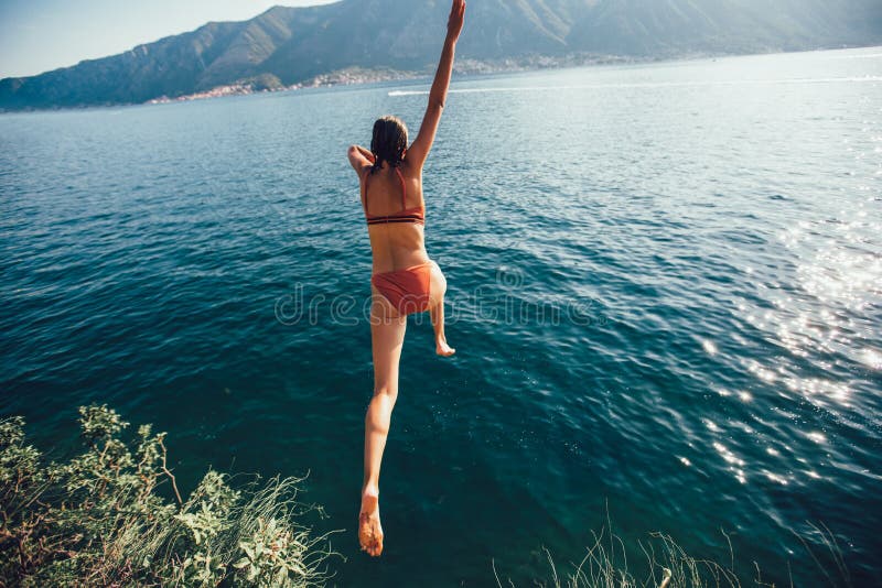 Woman jumping from a rock into the sea