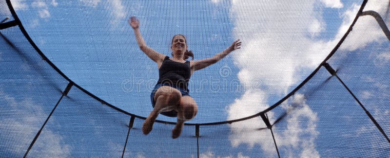 Happy young woman (age 30) jumps on a trampoline stock photo. 