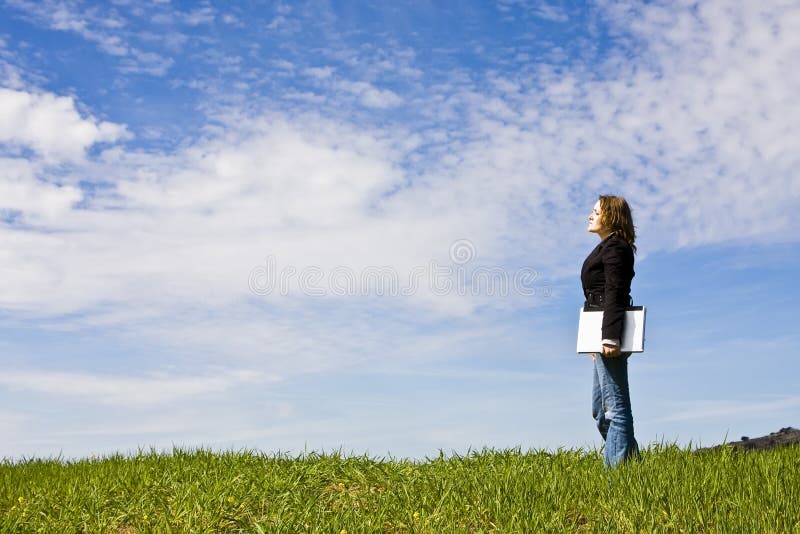 Young woman with laptop in meadow