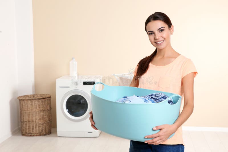 Young woman with laundry basket near washing machine at home stock photography Young woman with laundry basket near washing machine at home stock photography