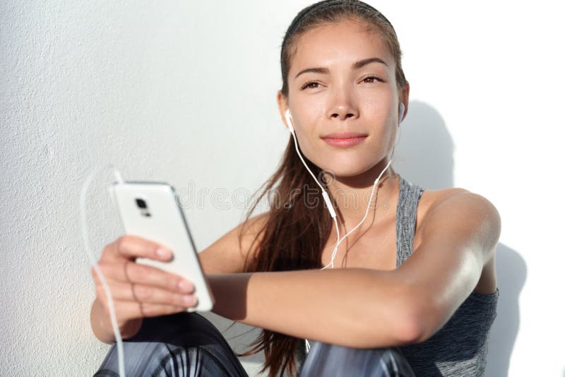 Young woman listening to motivation music with earphones on smart phone app