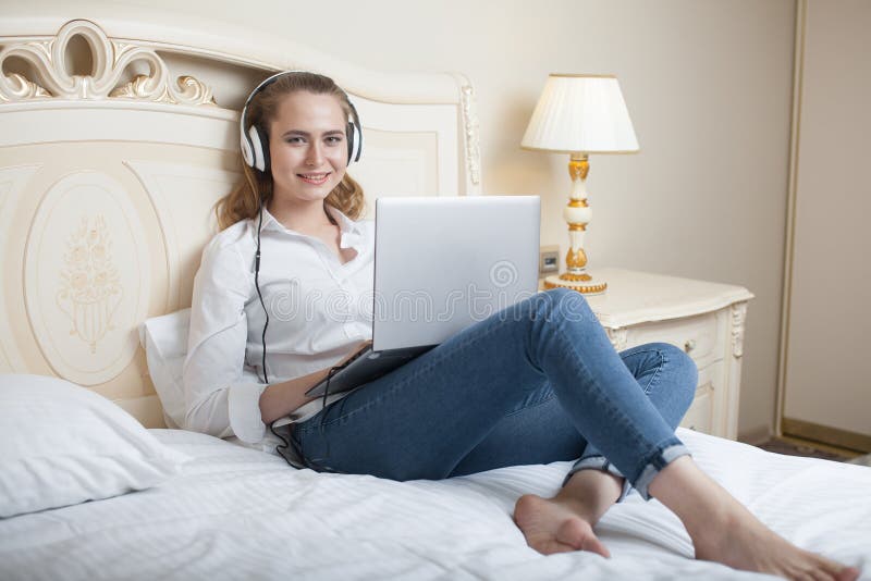 Junge Frau mit laptop auf dem Bett und hören Musik.