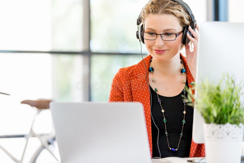 Young woman listening to the music while working on a computer stock image Young woman listening to the music while working on a computer stock image