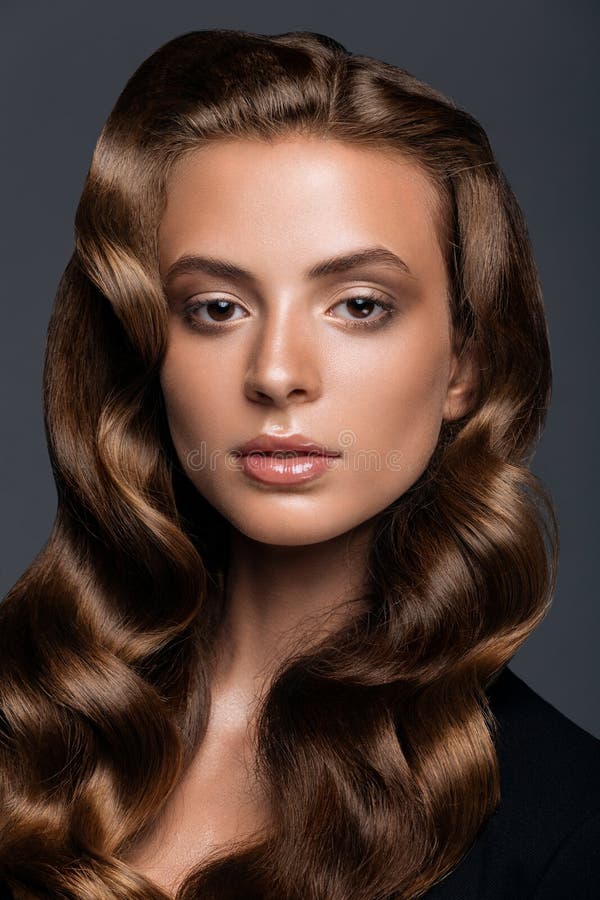 Young woman with long glossy curly hairstyle royalty free stock image