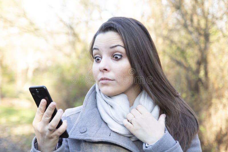 A young woman looking at the screen of her smartphone in the park stock images A young woman looking at the screen of her smartphone in the park stock images