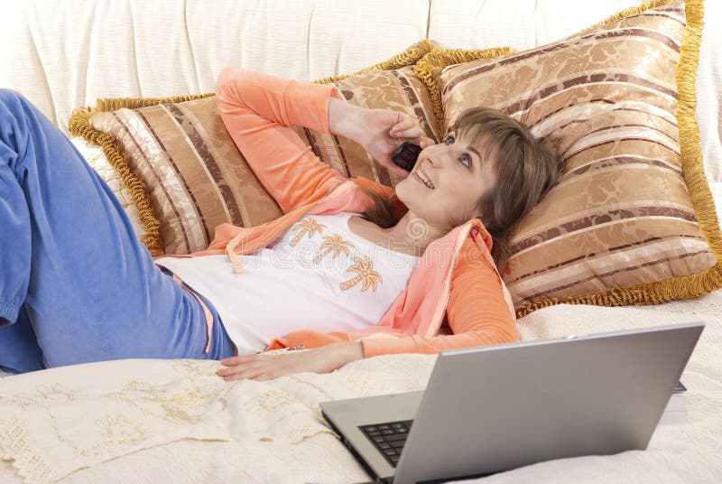 Young woman lying on bed with laptop