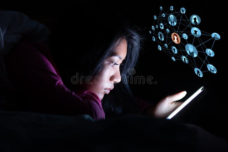 A young woman is lying in bed and using a social network on a smartphone stock image