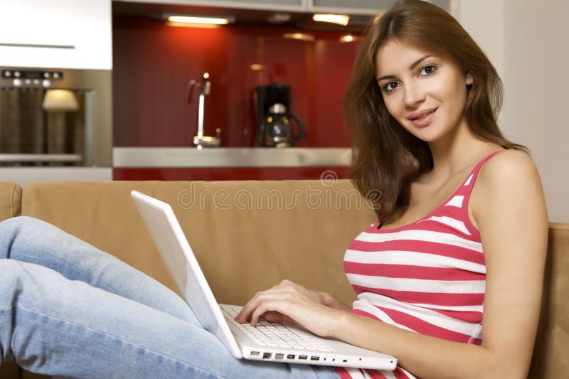 Young woman lying on a white sofa with a laptop.