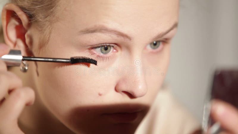 Young woman is making up her eyes.