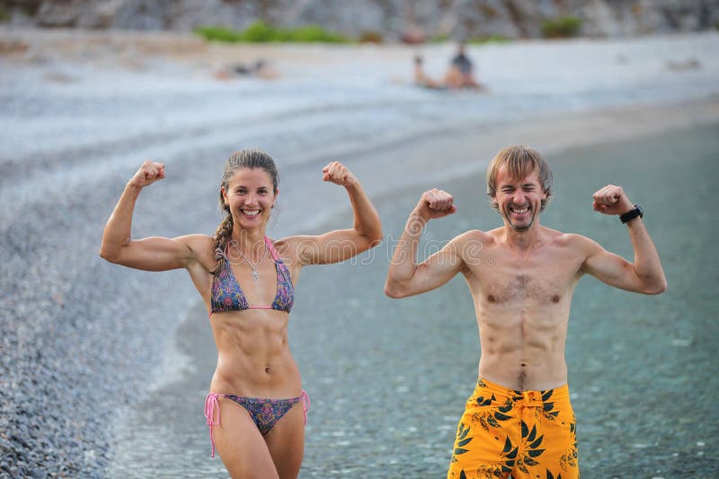 Young woman and man flexing their muscles jokingly