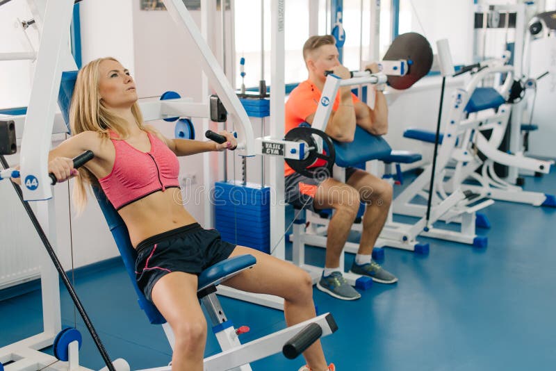 Young woman and man working out in gym. Couple making exercises for arms. Perfect bodies. royalty free stock images Young woman and man working out in gym. Couple making exercises for arms. Perfect bodies. royalty free stock images