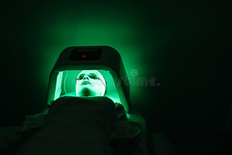 The young woman with mask and solarium glasses is relaxing in the solarium with green light in beauty salon. Skin care royalty free stock photo The young woman with mask and solarium glasses is relaxing in the solarium with green light in beauty salon. Skin care royalty free stock photo