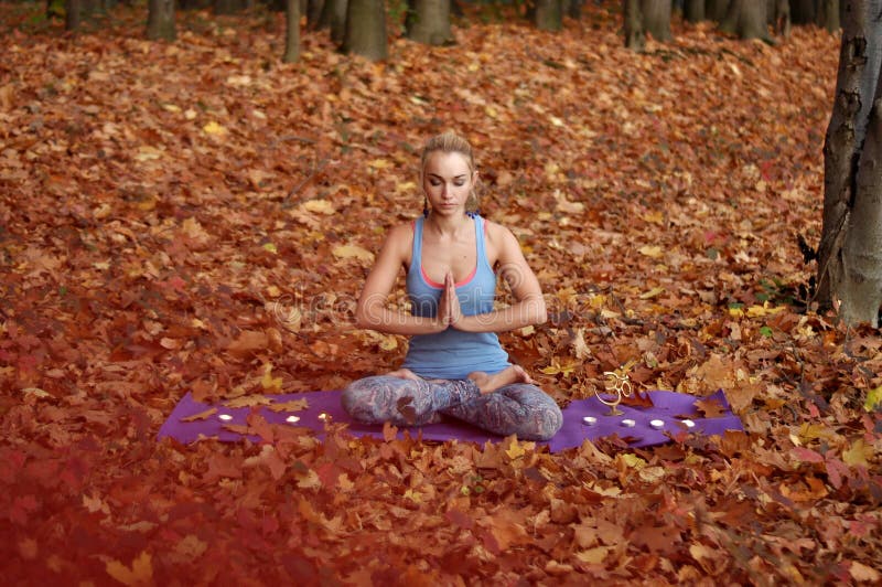 Young woman meditating in autumn forest