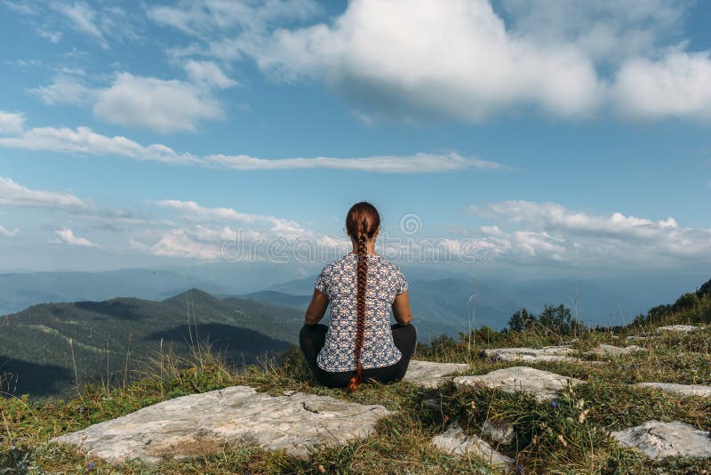 Young woman meditating or doing yoga while sits on rock top with magic mountain landscape royalty free stock photos Young woman meditating or doing yoga while sits on rock top with magic mountain landscape royalty free stock photos