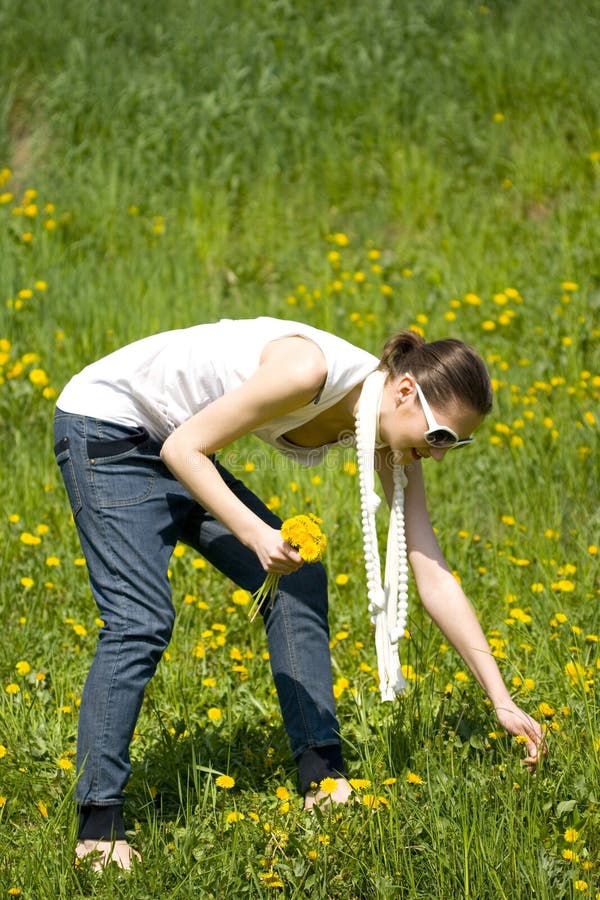 Young woman in nature picking flowers