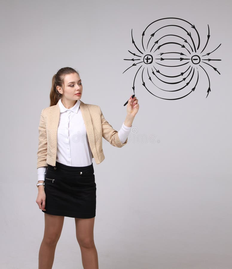 Young woman, physics teacher draws a diagram of the electric field stock photo Young woman, physics teacher draws a diagram of the electric field stock photo
