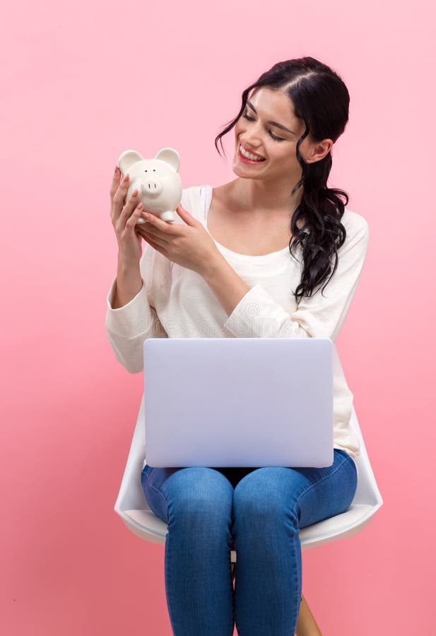 Young woman with piggy bank and laptop stock photo Young woman with piggy bank and laptop stock photo