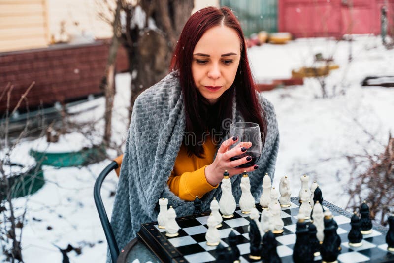 Focused man sipping alcoholic beverage while thinking about next chess move.  Stock Photo by DC_Studio