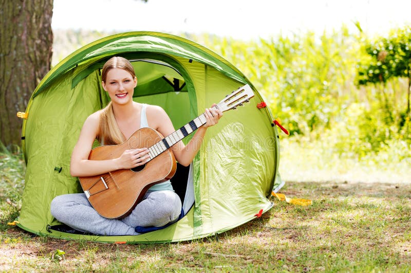 Young woman playing the guitar in a tent on the nature royalty free stock photos Young woman playing the guitar in a tent on the nature royalty free stock photos