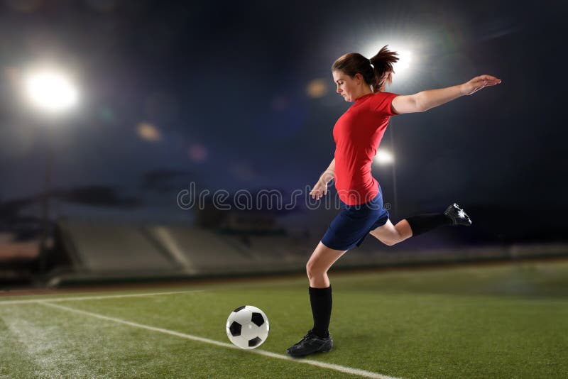 Young woman playing soccer insie a stadium at night