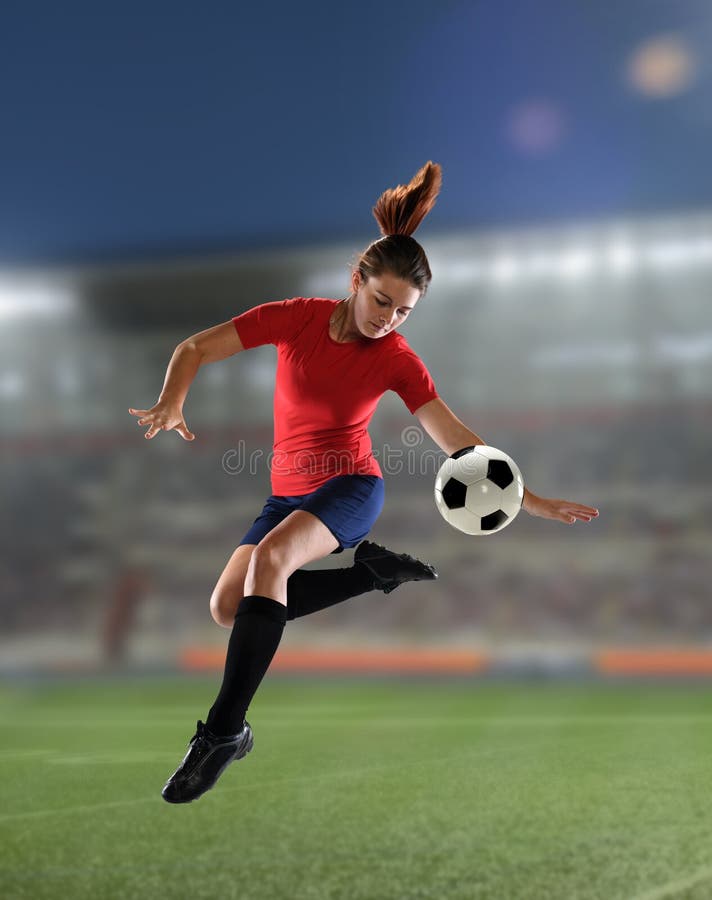 Young woman playing soccer insie a stadium at night