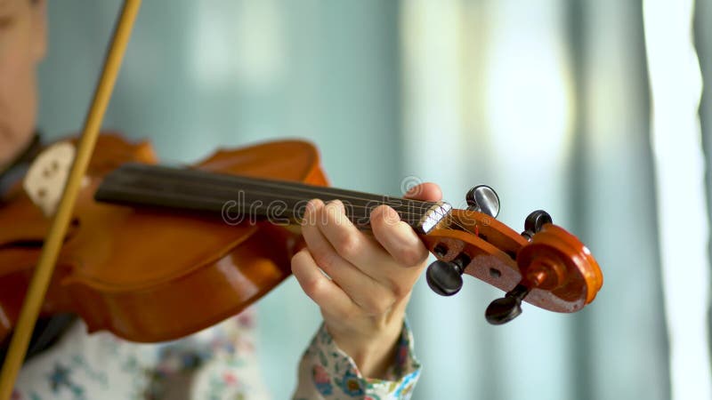 Young woman playing the violin. Hand of a female violinist on the fingerboard of a violin. Close up view