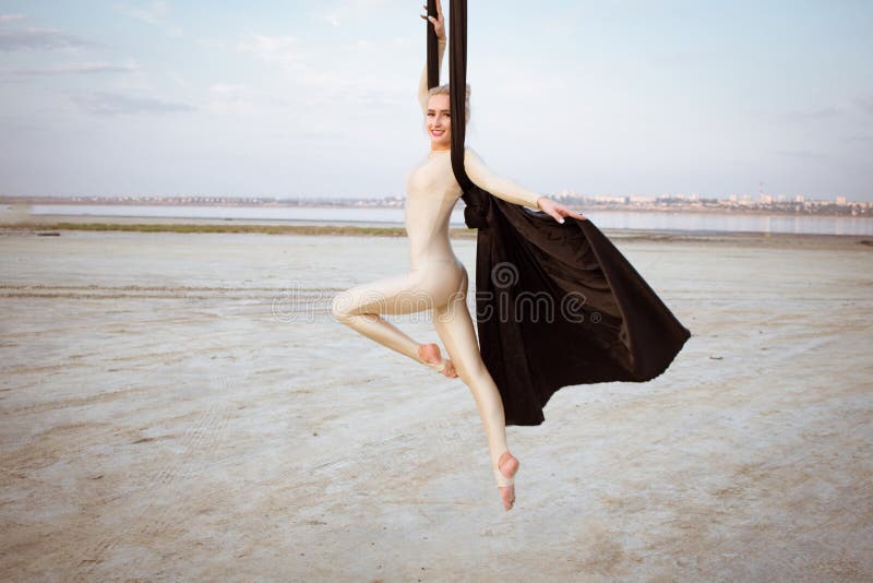 Fit woman in skinny skinny clothes dancing with aerial silk on a sky background, gymnast training on aerial silk. Fit woman in skinny skinny clothes dancing with aerial silk on a sky background, gymnast training on aerial silk