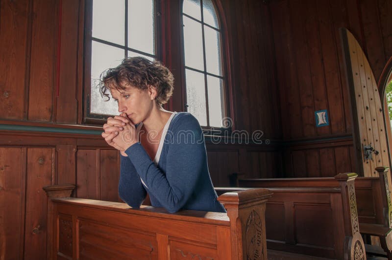 Young woman praying in the church stock photo Young woman praying in the church stock photo