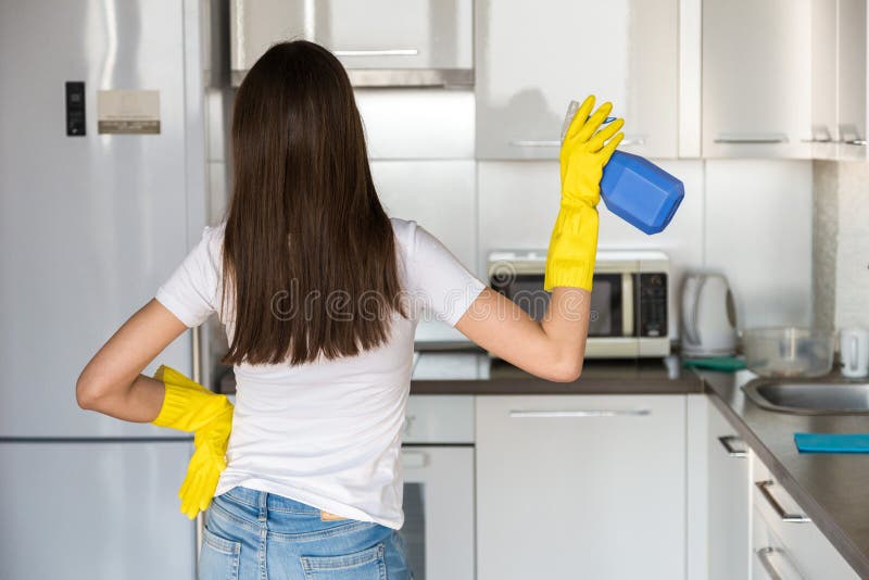 A young woman from a professional cleaning company cleans up at home. A man washes the kitchen in yellow gloves with stock image A young woman from a professional cleaning company cleans up at home. A man washes the kitchen in yellow gloves with stock image